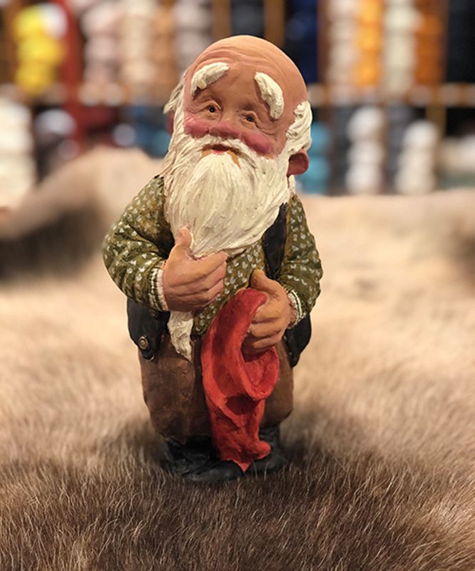 Midthun-nisse stående med lua i handa